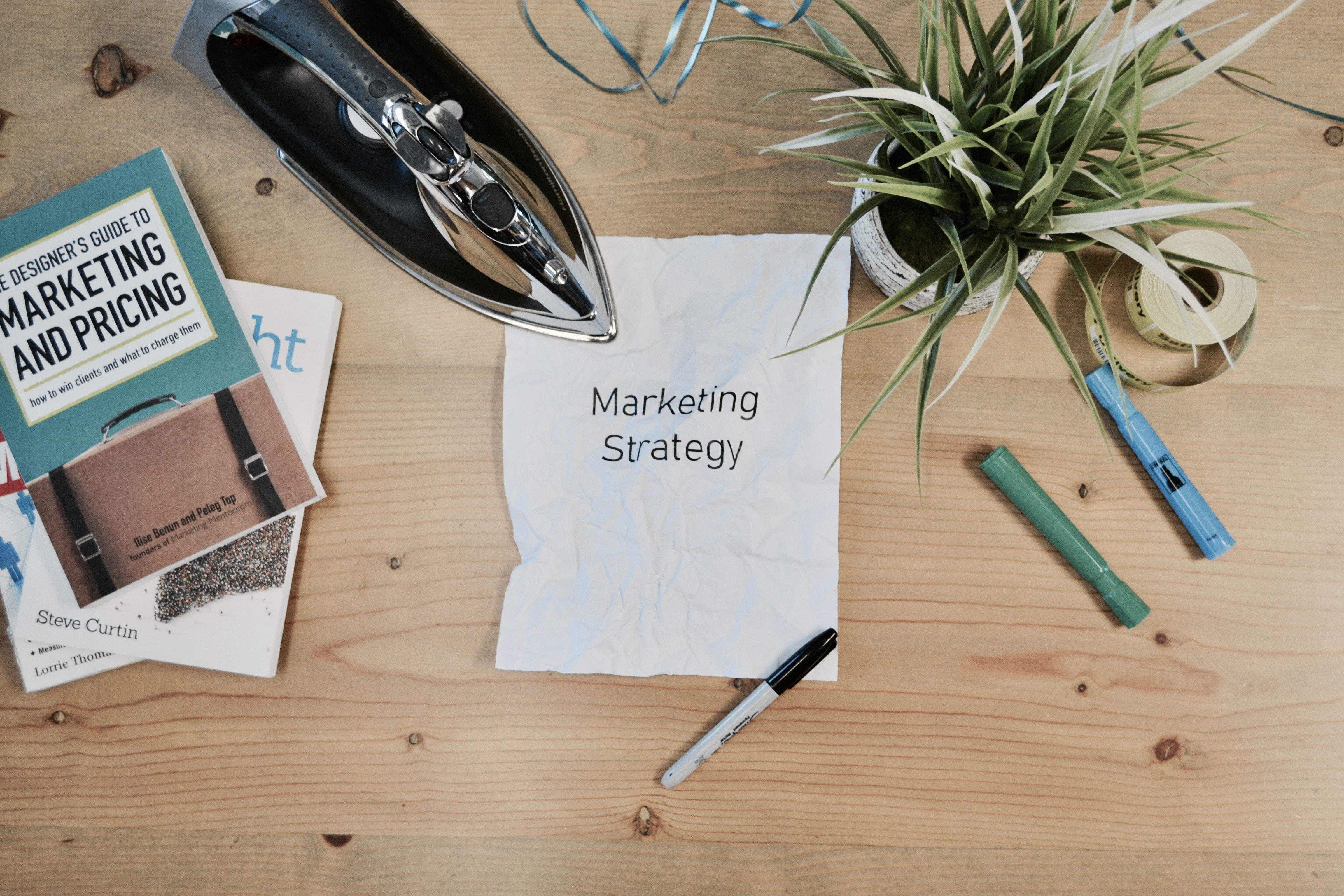"A table of stationary and decor with a paper that reads Marketing Strategy in the center."