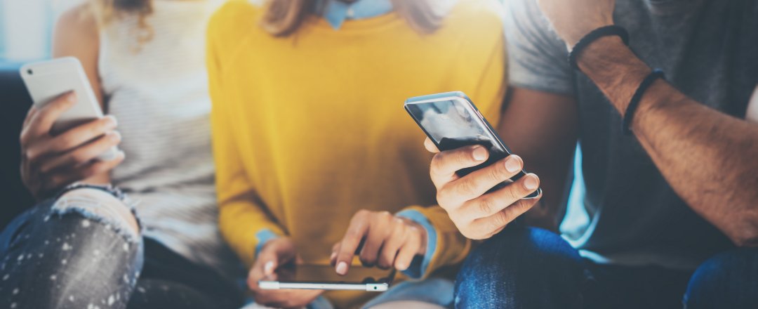 group of three people sitting down looking at their phones