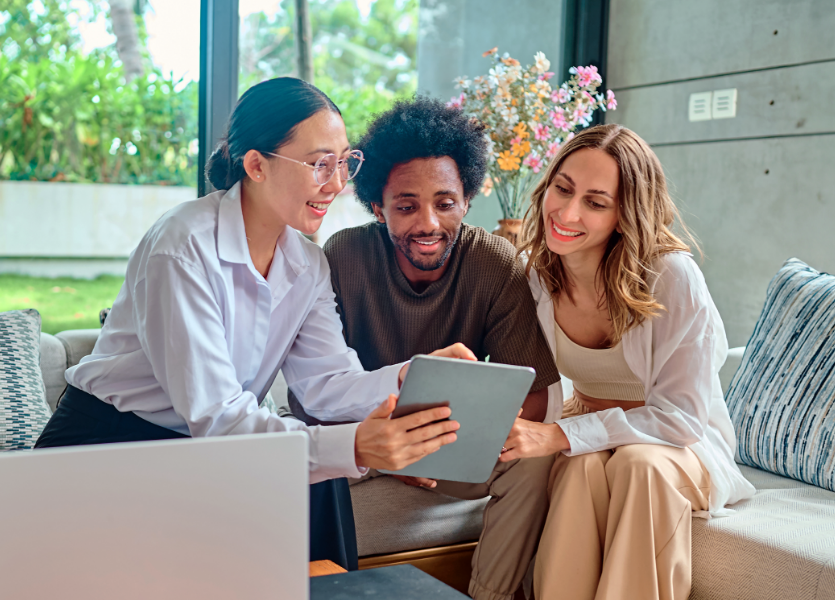 Three people smiling, looking at a phone screen. 