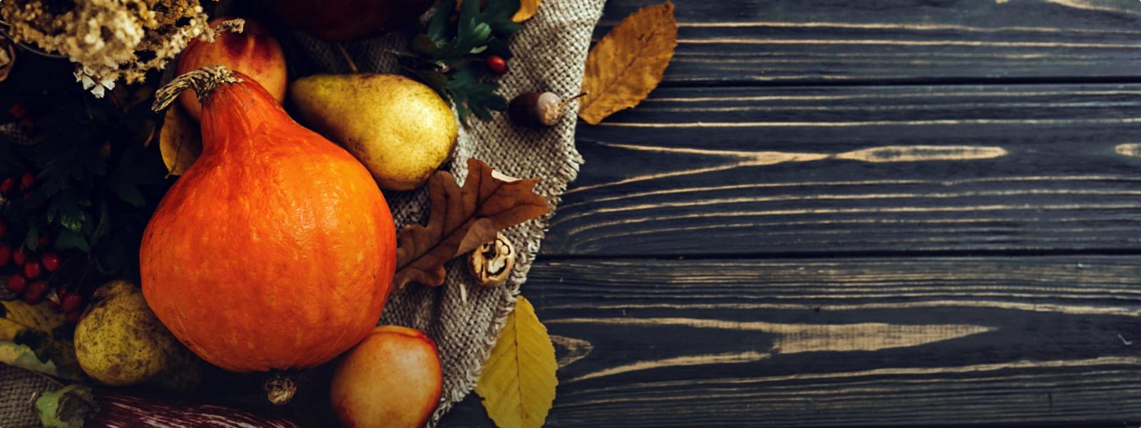 A collection of Thanksgiving gourds on a wooden table. 