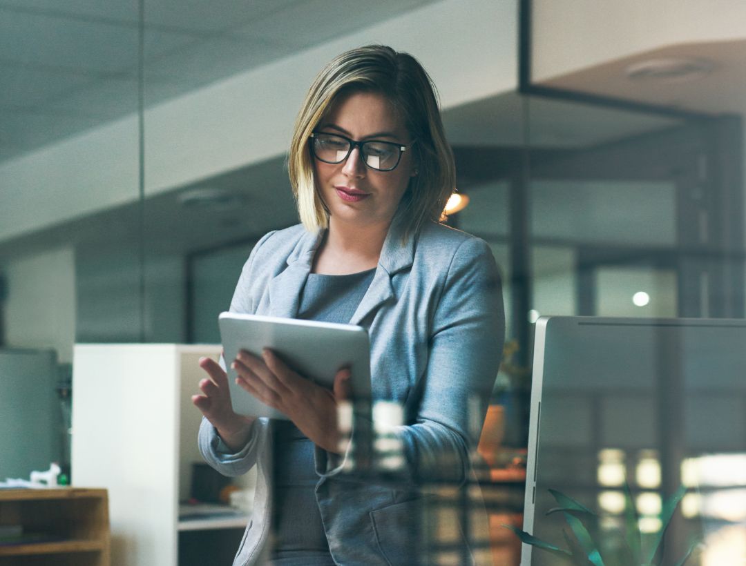 Business woman standing in an office looking at the tablet