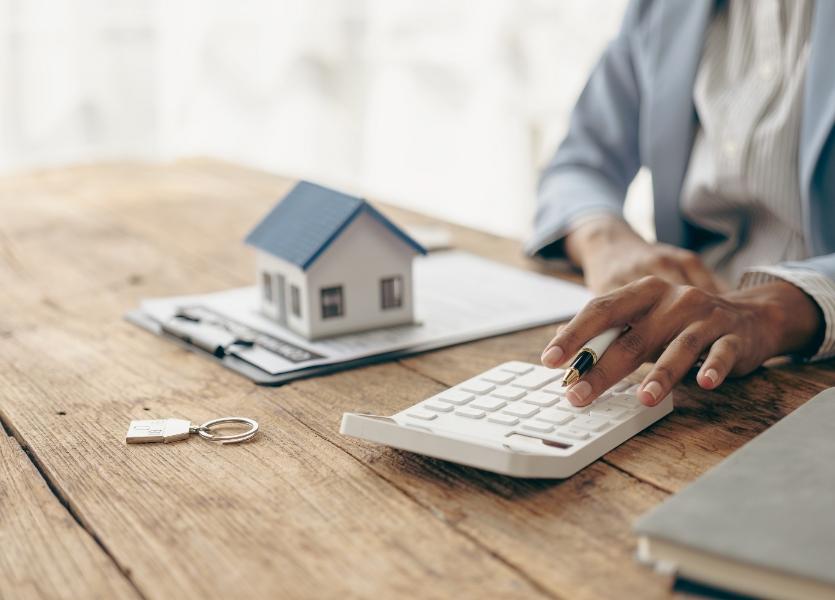 A model of a house on a table in front of a person.