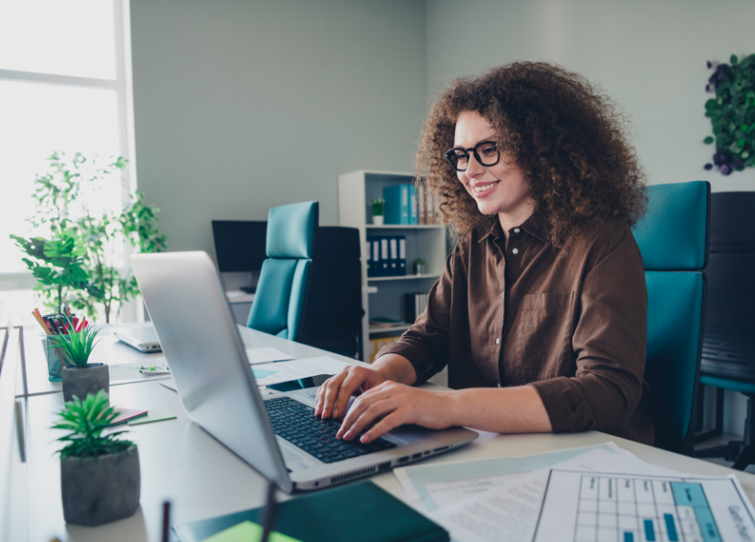 A professional uses a computer, smiling.