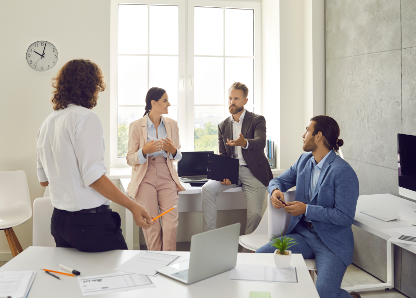 A group of people talking in an office. 